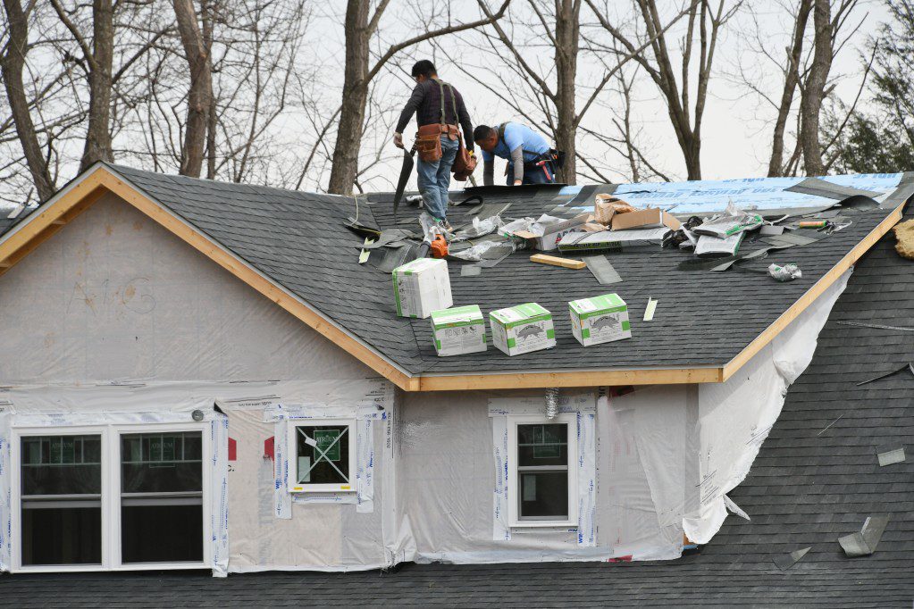 Contractors working on a new shingled roof
